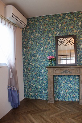 ウィリアムモリスというデザイナーの紙素材の壁紙の部屋、壁際には鏡台がある