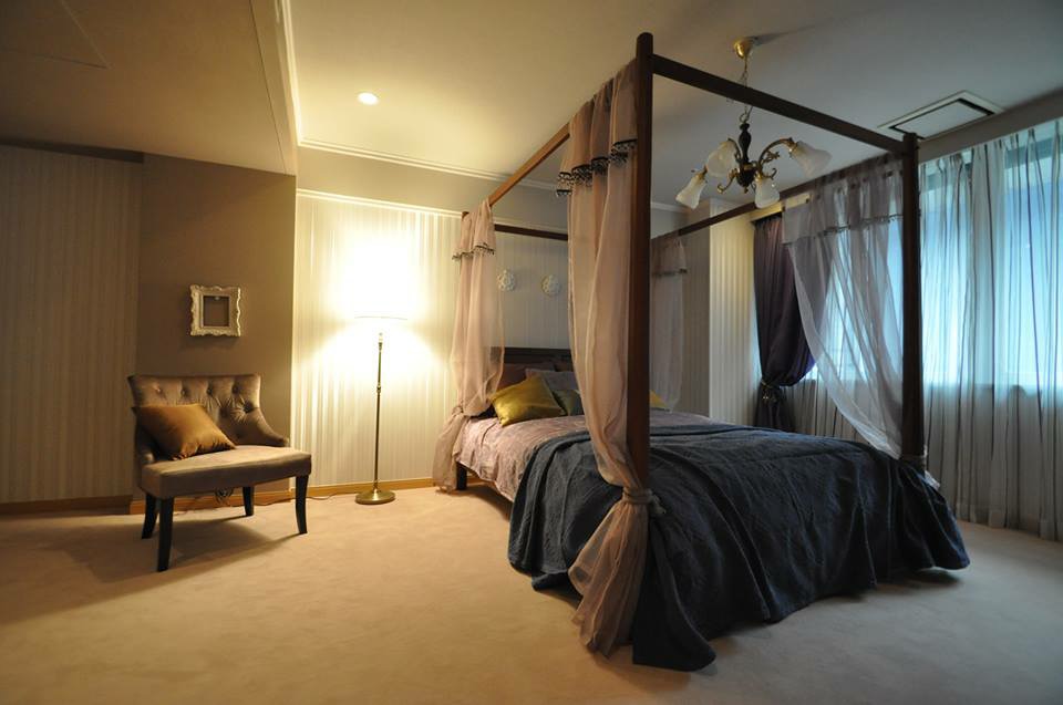 大きなベッドとソファー、スタンド照明が置かれた部屋