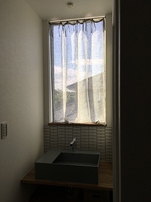 洗面台の前にある窓にかかるカーテン