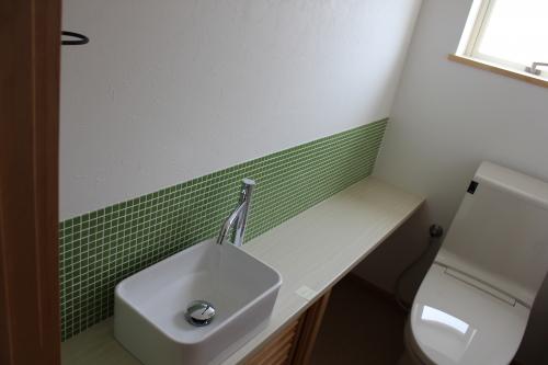 壁にグリーンのタイルが貼ってあるトイレ