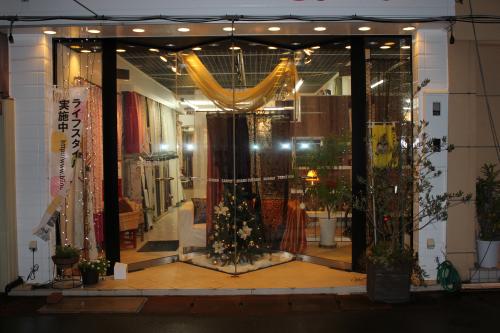 店の外観写真、日が暮れて照明が輝く店内にはクリスマスツリーが飾られている