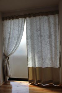 リーフ柄の生地と無地の生地を選び縫い合わせたカーテンが掛かった窓