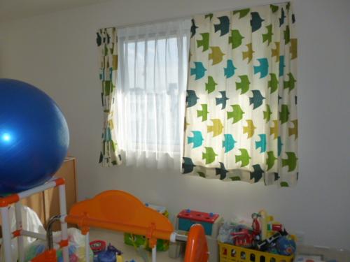 ベージュ地に青、緑、黄の鳥モチーフ柄のカーテンが掛かった窓
