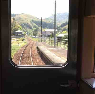 電車の窓から見える線路と山の景色。
