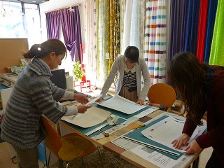 まちゼミでのインテリア講習会の写真、参加者の方々がカッターで壁紙を切る作業をしている